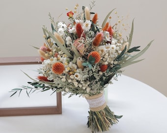 May include: A dried flower bouquet featuring a variety of textures and colors. The arrangement includes orange, white, and green elements, tied with twine and lace. The bouquet is a natural, rustic style, suitable for home decor or special events.
