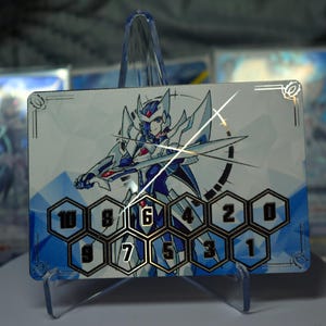 May include: A trading card featuring a futuristic warrior with a sword, in shades of blue, white, and silver. The card has a series of numbered hexagonal spaces at the bottom. Other cards are visible in the background.