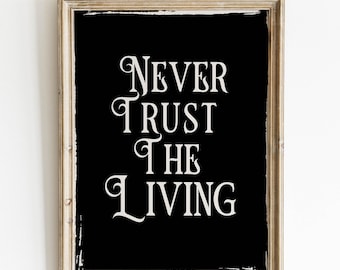 May include: A framed black and white print with the text "NEVER TRUST THE LIVING" in a decorative font.