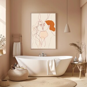 May include: A line drawing of two people kissing, with one person having red hair. The drawing is framed and hanging on a wall in a bathroom with a white bathtub and a brown rug.