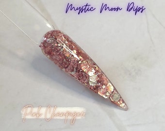 May include: Pink Champagne nail dip powder with a shimmery finish. The powder is shown on a nail tip and has a mix of pink, gold, and white glitter.