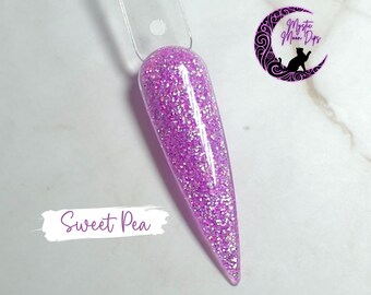 Puede incluir: Primer plano de un polvo de inmersión para uñas de color morado claro con un acabado brillante. El polvo de inmersión para uñas está etiquetado como "Sweet Pea".