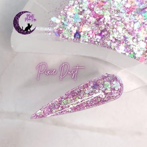 May include: A close-up of a clear nail tip with a pink and iridescent glitter polish. The glitter is a mix of small and large hex glitter, and the polish is labeled "Pixie Dust".