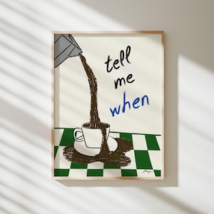 May include: A framed art print featuring a coffee cup and saucer with coffee pouring from a container. The words "tell me when" are written in black and blue. The background has a green and white checkered pattern.