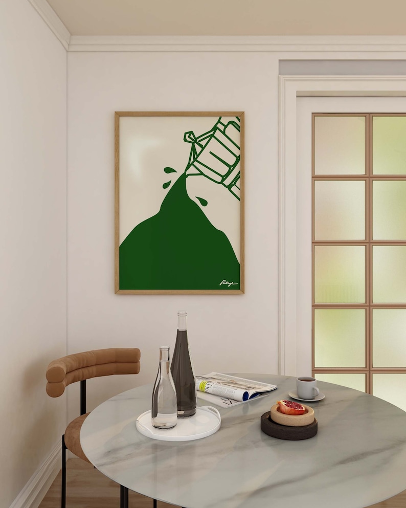 May include: A framed illustration of a green mountain with a white outline of a person pouring water from a bucket. The illustration is on a white background and the frame is wood.