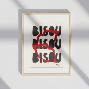 Op de afbeelding: Een ingelijst drukwerk met het woord "BISOU" dat drie keer in zwarte tekst wordt herhaald. Het woord wordt gedeeltelijk bedekt door een rode, penseelstreep-achtige vorm.