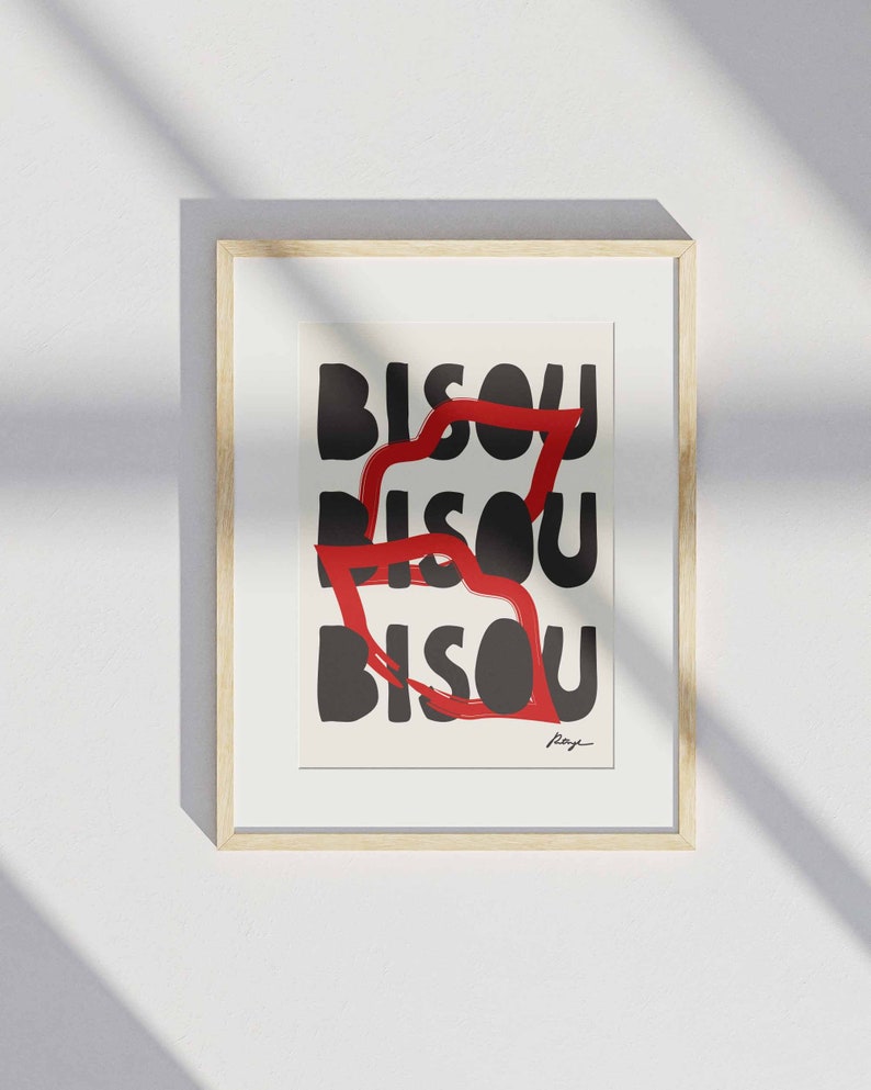 Op de afbeelding: Een ingelijst drukwerk met het woord "BISOU" dat drie keer in zwarte tekst wordt herhaald. Het woord wordt gedeeltelijk bedekt door een rode, penseelstreep-achtige vorm.
