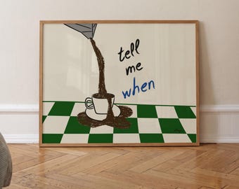 May include: A framed wall art print featuring a graphic illustration of dark liquid pouring from a grey vessel into a white coffee cup on a saucer. The text "tell me when" is written in black and blue. The scene sits on a green and white checkered floor.
