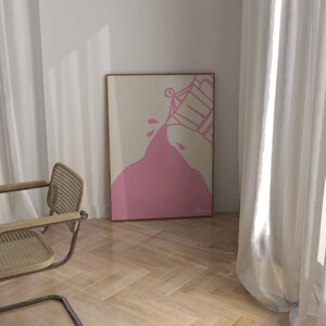 May include: A pink abstract art print with a white background. The print features a pink shape that looks like a liquid being poured from a container. The print is framed in a light wood frame.