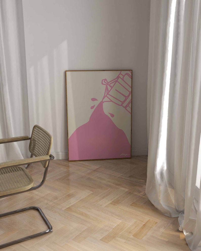 May include: A pink abstract art print with a white background. The print features a pink shape that looks like a liquid being poured from a container. The print is framed in a light wood frame.