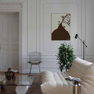 May include: A white sofa with a white throw pillow and a brown abstract art print hanging on the wall above it. A small glass table with a magazine on it sits in front of the sofa. A potted plant is in the corner of the room.