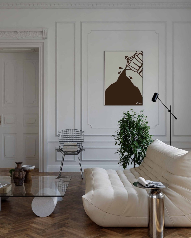 May include: A white sofa with a white throw pillow and a brown abstract art print hanging on the wall above it. A small glass table with a magazine on it sits in front of the sofa. A potted plant is in the corner of the room.