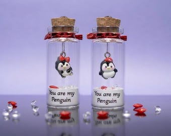 May include: Two glass bottles with cork stoppers, red ribbon, and penguin charms. Each bottle has the text "You are my Penguin" on the front. The penguins are black, white, and red.