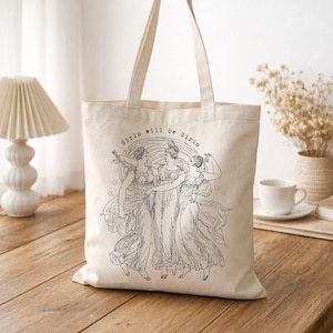 May include: Cream-colored tote bag featuring a black illustration of three women in flowing gowns, with the text "Girls will be Girls" above the image. The bag has two handles for carrying.