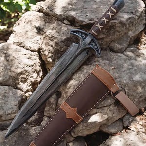May include: A detailed image of a dagger and sheath. The dagger has a silver blade and a brown leather-wrapped handle with a decorative crossguard. The sheath is brown leather with white stitching and a tan leather accent.