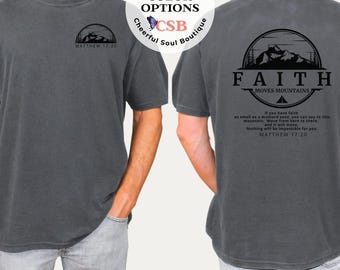 May include: Pepper-colored t-shirt with a mountain and tree design. The front has a small mountain graphic and the text "MATTHEW 17:20". The back features a circular design with "FAITH MOVES MOUNTAINS" and a Bible verse. "MORE COLOR OPTIONS" is also visible.
