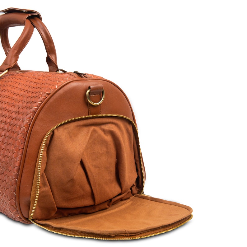 May include: A brown leather duffel bag with a woven pattern and a gold zipper. The bag is open and the inside is lined with brown fabric.