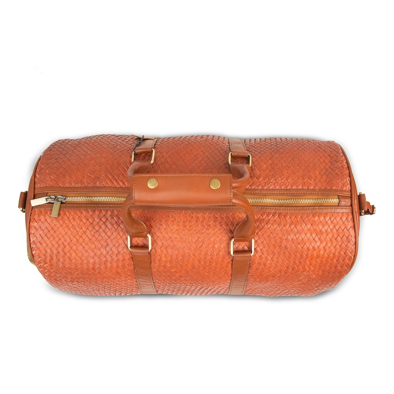 May include: A brown leather woven duffel bag with gold zipper pulls and brass hardware.