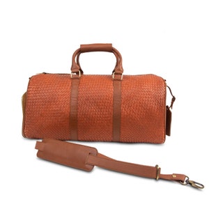 May include: A brown leather duffel bag with a woven pattern and a matching shoulder strap.