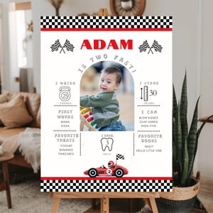 Könnte beinhalten: Ein rot-weiß kariertes Meilenstein-Poster mit einem Foto eines kleinen Jungen. Das Poster enthält den Namen des Babys, Adam, und Details zu seinem Alter, Gewicht, Größe, Lieblingsessen und Büchern. Das Poster ist im Rennauto-Stil dekoriert.
