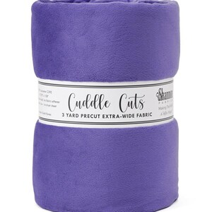 May include: A roll of purple Cuddle Cuts fabric. The fabric is extra-wide and precut to 3 yards. The fabric is wrapped with a white label that has the words "Cuddle Cuts" printed on it.