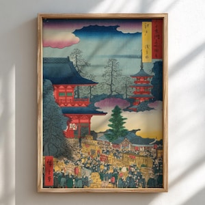 Puede incluir: Grabado japonés enmarcado que representa una bulliciosa escena callejera con arquitectura tradicional. La obra de arte presenta edificios rojos y azules, una pagoda y una multitud de personas. El cielo transita del rosa al azul, y el grabado está en un marco de madera.