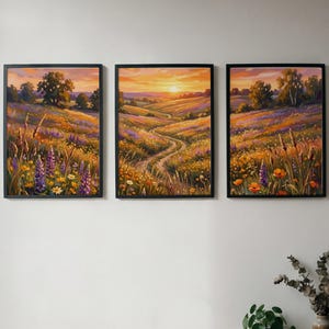 May include: A triptych of three rectangular framed wall art prints featuring a continuous landscape painting of a rolling meadow at sunset. The scene displays vibrant orange, yellow, and purple wildflowers under a golden sky with a winding dirt path.