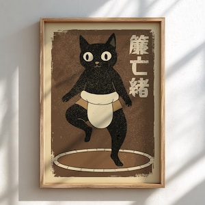 May include: Framed art print depicting a black cat in a sumo wrestler's attire. The cat is positioned in a sumo ring, with Japanese text on the right. The background is a textured brown, and the frame is a light wood colour.