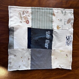 May include: A rectangular patchwork quilt featuring various fabric patterns and colors. The quilt includes animal prints, striped patterns, and the word "Brother" in blue. The quilt is bordered with a white fabric.