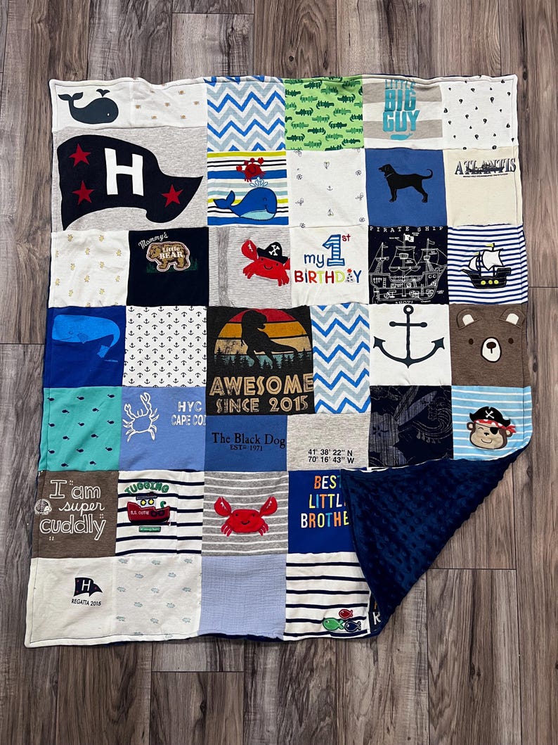 May include: A patchwork quilt made from various fabric squares, featuring nautical and animal-themed designs. The quilt includes images of whales, anchors, crabs, and the text "Awesome Since 2015". The quilt has a navy blue, textured backing.