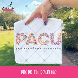 May include: White t-shirt with the letters "PACU" in colorful floral design. Below the letters is the text "post anesthesia care nurse". The shirt is held up by a hand with a gold bracelet and blue nail polish.