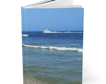 Puede incluir: Un libro con una cubierta azul que presenta una fotografía de un barco blanco en un océano azul con olas blancas.