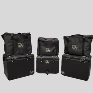 May include: Four black luggage bags with silver accents and a logo on the front. The bags are arranged in two rows of two. The bags are made of a durable material and have a sleek design.