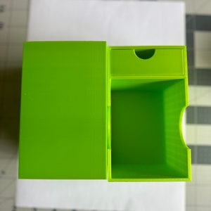 May include: A bright green, two-piece storage box with a drawer. The box is made of plastic and has a smooth, matte finish.