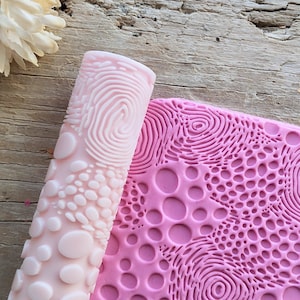 Puede incluir: Dos rodillos de amasar de silicona rosa para hornear. Uno tiene un patrón de espiral y el otro tiene un patrón de círculos y puntos.