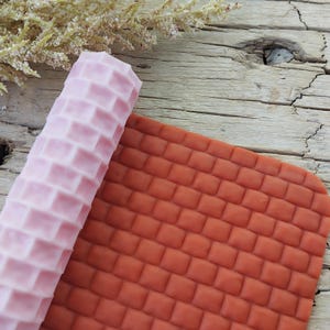 May include: A pink and white textured rolling pin and a brown textured silicone mat for baking and decorating.