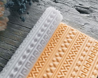 May include: A white and orange silicone rolling pin with a geometric pattern. The rolling pin is used for decorating cakes and pastries.