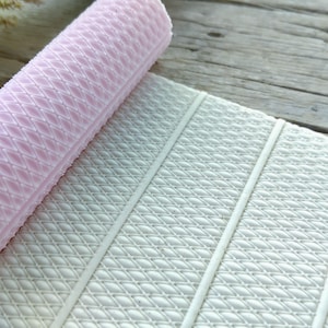 May include: A pink silicone rolling pin with a diamond pattern and a white silicone baking mat with a similar pattern.