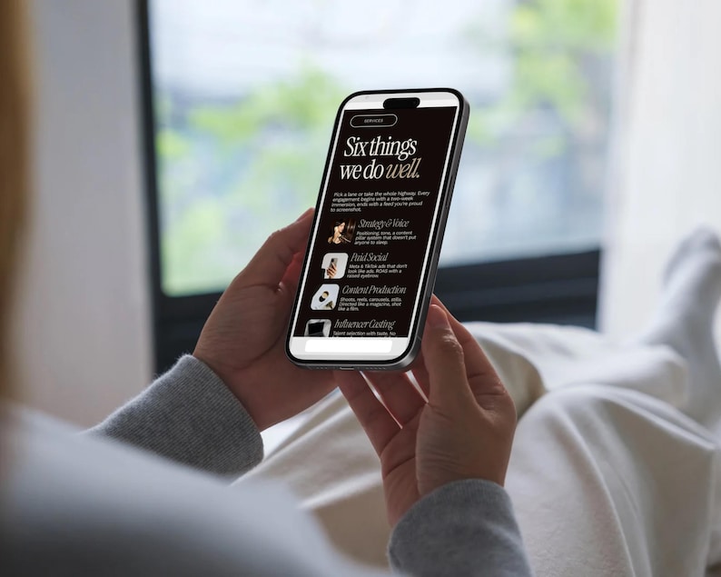 May include: A smartphone displaying a dark-themed webpage with the white text header Six things we do well. The screen lists services including Strategy & Voice, Fluid Social, Content Production, and Influencer Casting with small icons.