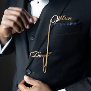 May include: Two gold nameplate lapel pins with a chain connecting them. The top pin reads "Wilson" and the bottom pin reads "Donnell".