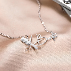 May include: Silver necklace with a comb and scissors charm, and the word "Beaute" written in cursive.