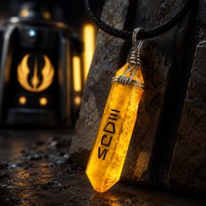 May include: A yellow crystal pendant with black text, hanging from a black cord. The crystal is encased in silver wire. The background shows a dark, textured surface and a blurred, illuminated emblem.