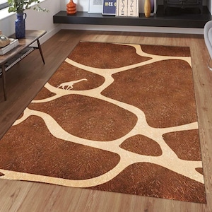 May include: A brown and cream area rug with a giraffe print. The rug has a textured surface and a white outline of a giraffe walking across the rug.