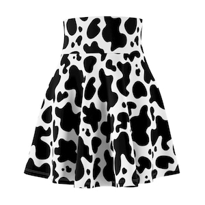 Può includere: Una gonna svasata con stampa a mucca in bianco e nero. La gonna ha una vita alta e una silhouette fluida. Il tessuto è ricoperto da macchie nere irregolari su sfondo bianco, creando un motivo audace e giocoso.