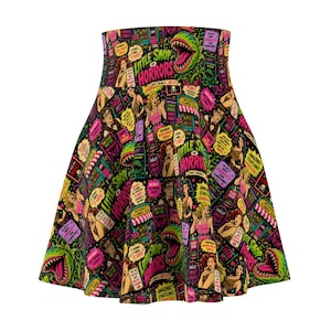 May include: A high-waisted skater skirt featuring a vibrant, all-over print inspired by Little Shop of Horrors. The design includes comic-style illustrations of Audrey II, characters, and text like "Little Shop of Horrors" and "Feed Me" in neon pink, green, and yellow.