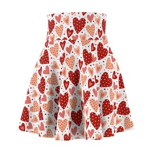 May include: A high-waisted skater skirt featuring an all-over print of red and light pink hearts on a white background. The red hearts are decorated with small white polka dots, while the pink hearts are solid or have small dots.