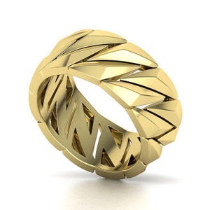 Peut inclure: Une bague dorée au design géométrique. La bague présente une série de formes triangulaires disposées autour de l'anneau, créant un aspect texturé et moderne. L'intérieur de la bague présente un motif découpé.
