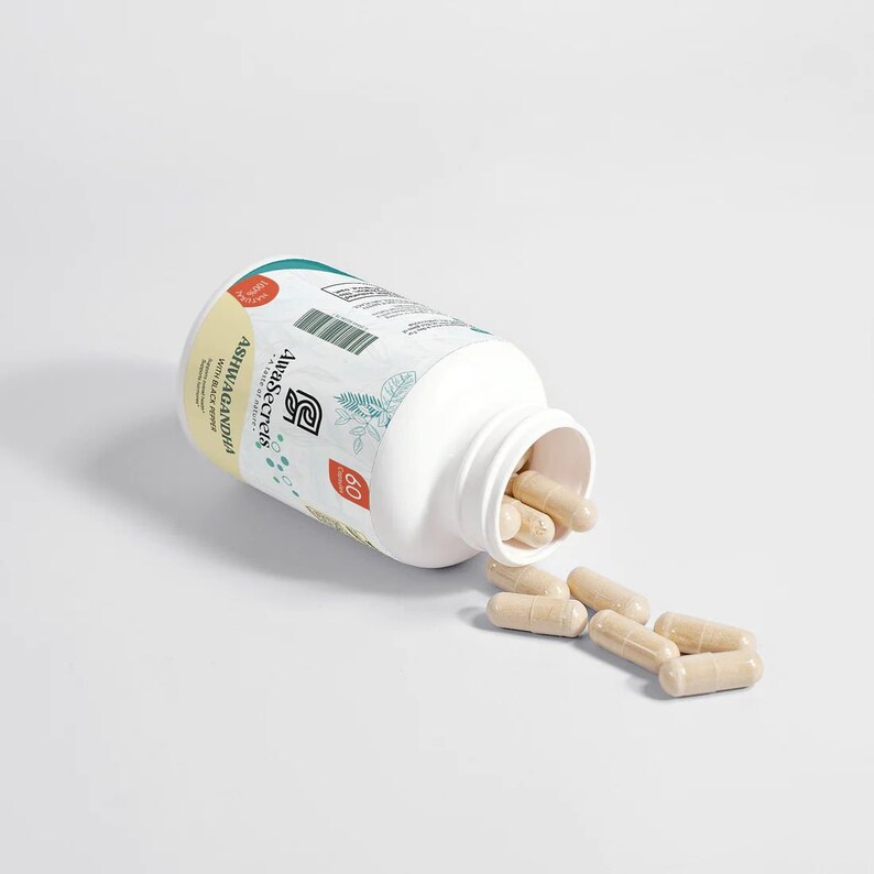 Puede incluir: Una botella blanca de c&aacute;psulas de Ashwagandha con extracto de pimienta negra. La botella est&aacute; abierta y se han derramado algunas c&aacute;psulas. La etiqueta de la botella dice "Ashwagandha with Black Pepper Extract" y "60 Capsules".