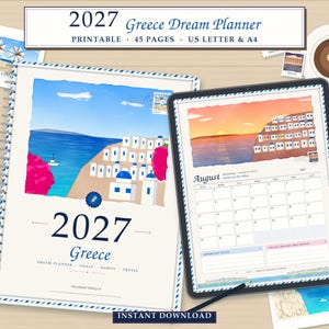 May include: A 2027 Greece Dream Planner printable featuring a spiral-bound cover with a blue and white Greek coastal illustration, a tablet displaying an August calendar page, and small decorative prints of Greek scenery on a wooden surface.