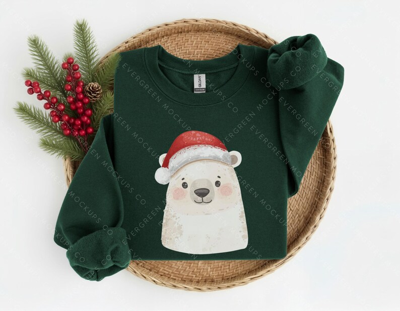 May include: A dark green long-sleeve sweatshirt featuring a graphic of a white polar bear wearing a red and white Santa hat. The sweatshirt has a crew neckline and is displayed with a sprig of green pine needles and red berries.